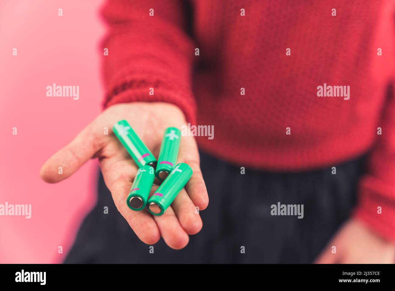 Zwei Handflächen einer kaukasischen Person mit vier Batterien auf rosa Hintergrund. Ökologie und Recycling-Konzept. Hochwertige Fotos Stockfoto