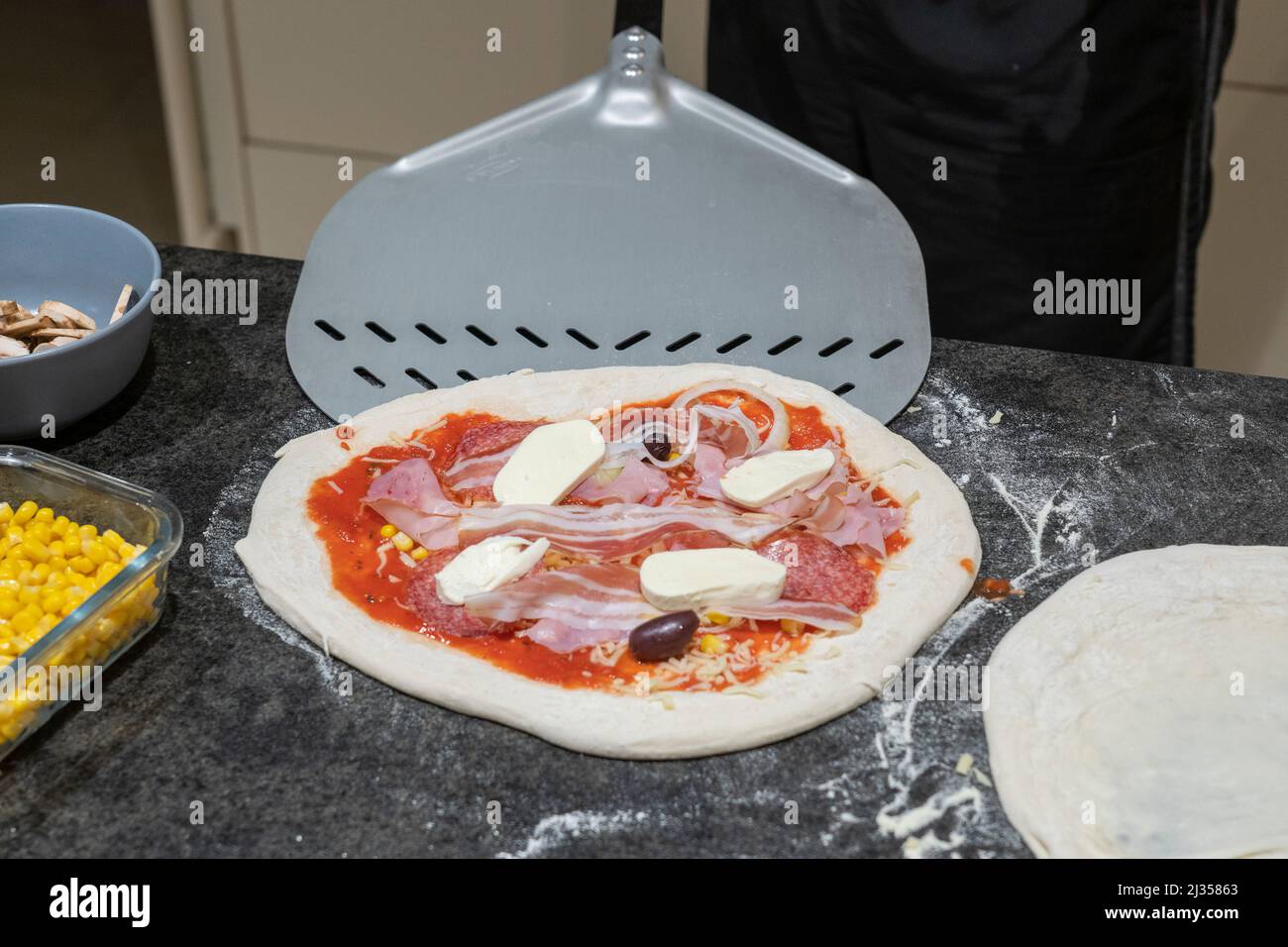 Ein Mann, der mit einer professionellen Pizzaschaufel eine hausgemachte Pizza serviert. Österreich Stockfoto