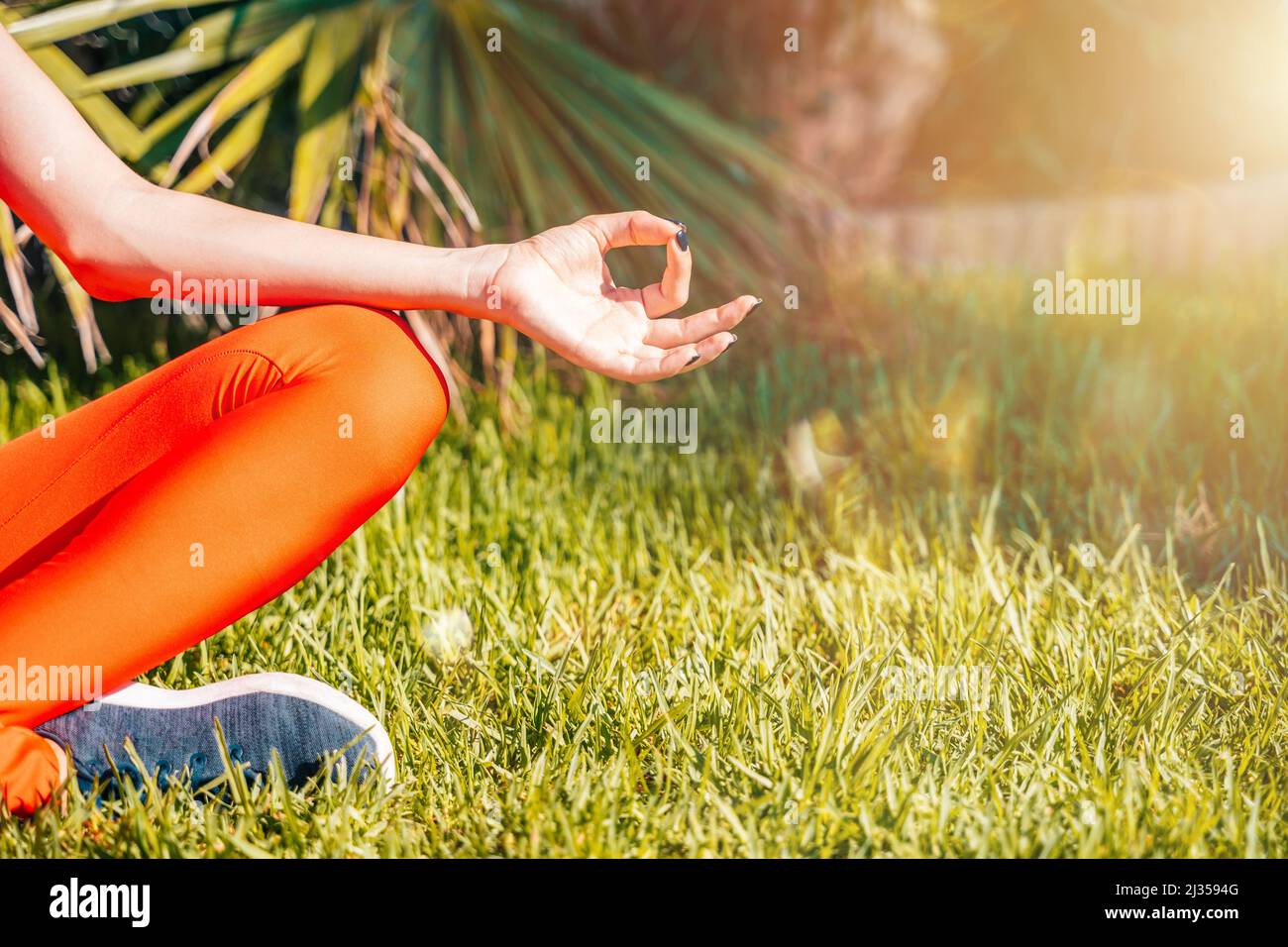 Frau, die sich in Yoga-Position in einem grünen Garten entspannt Stockfoto