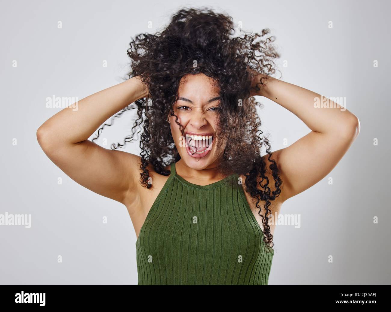Der natürliche Haarkampf ist real. Studioaufnahme einer Frau mit unordentlichen Haaren, die vor einem grauen Hintergrund posiert. Stockfoto