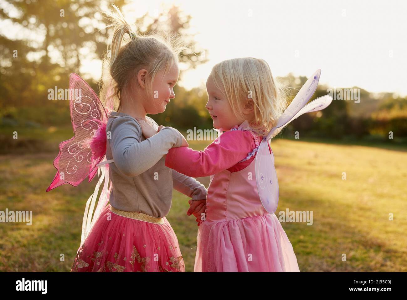 Oh, was für ein Spaß es ist, kleine Kinder zu sein. Eine kurze Aufnahme von zwei kleinen Mädchen, die draußen zusammen spielen. Stockfoto