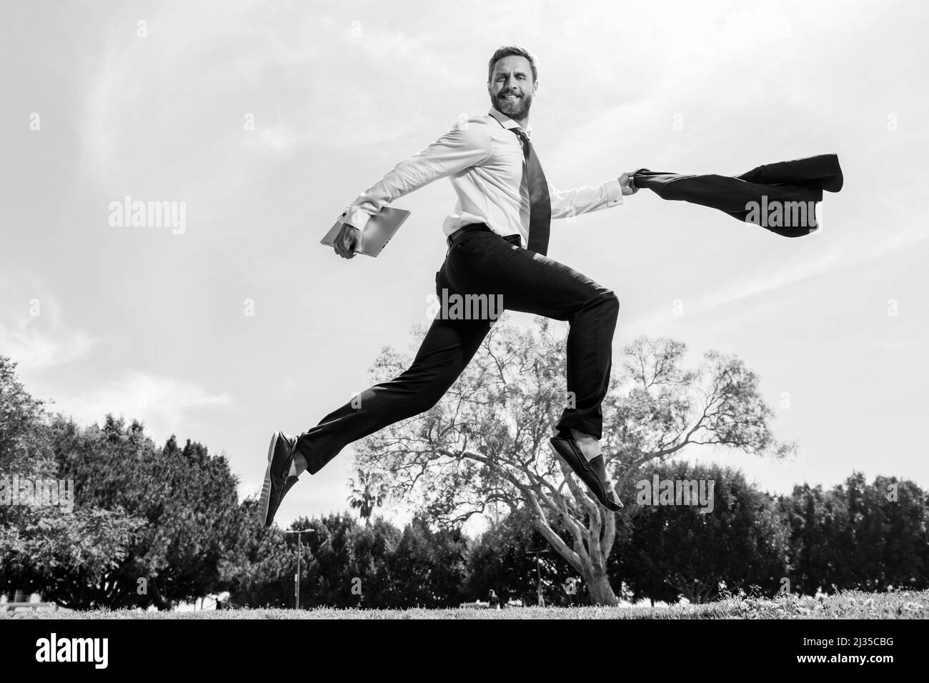 Geschäftsmann im Anzug, der über den Stadtpark springt. Schnelles Geschäftskonzept. Stockfoto
