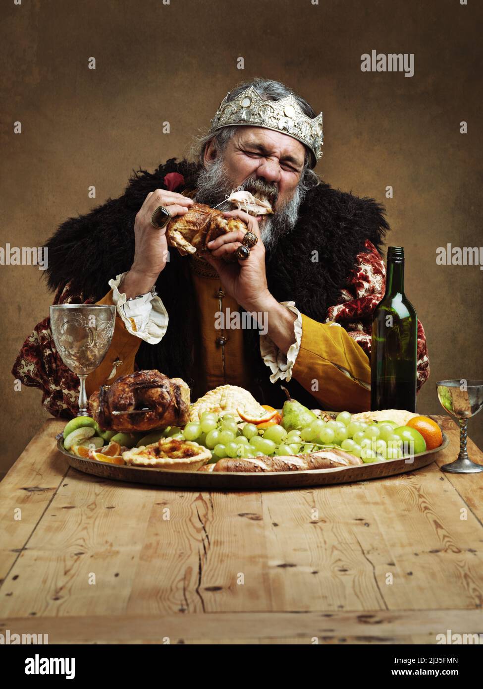 Das Regieren ist ein hungriger Geschäftsbetrieb. Ein reifer König, der allein in einem Bankettsaal schmallt. Stockfoto