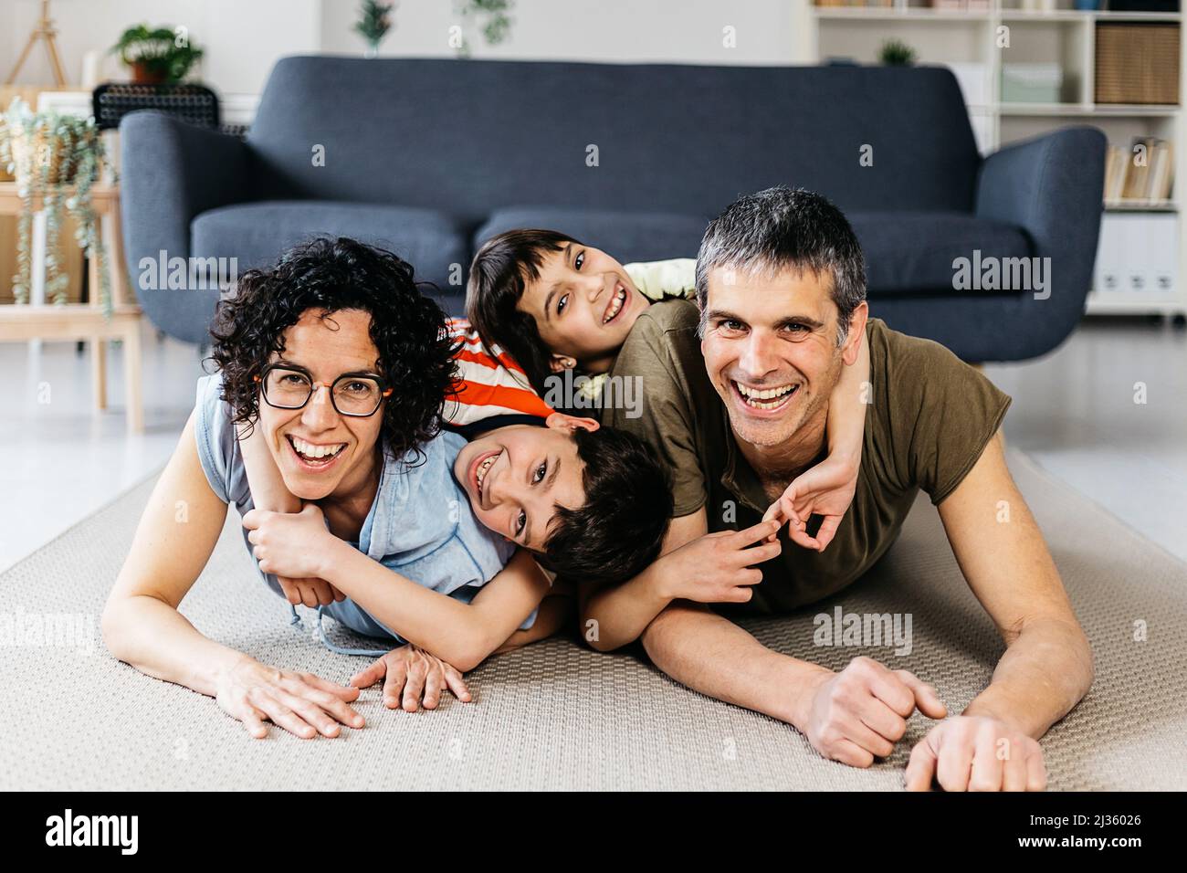 Eine glückliche europäische Familie zu Hause, die sich beim Entspannen auf dem Teppich umarmte Stockfoto