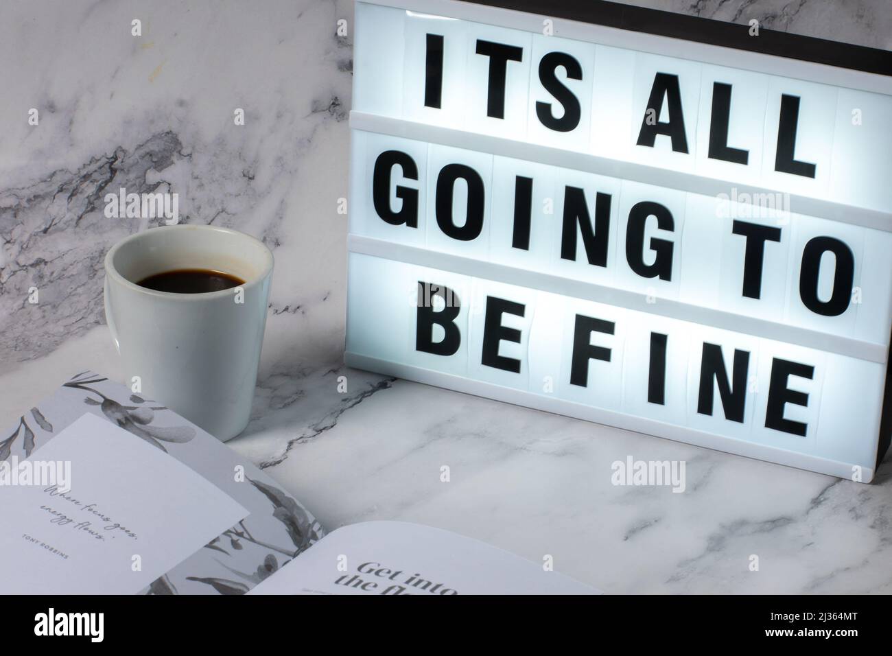 Eine entspannende Selbstpflege mit einem inspirierenden Zitat auf einer Leuchtbox und einer Tasse Kaffee, während Sie ein Selfcare-Tagebuch lesen. Stockfoto
