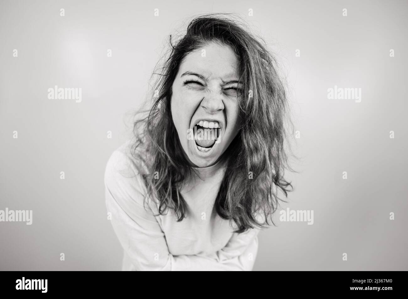 Nahaufnahme Porträt einer verrückten Frau in Zwangsjacke auf weißem Hintergrund. Monochrom. Stockfoto