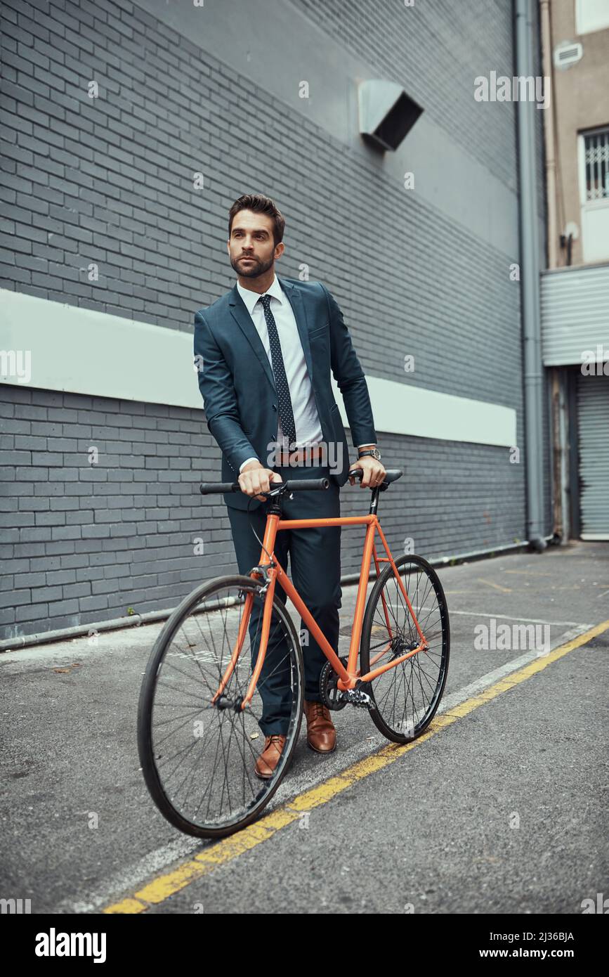 Hes war sich immer bewusst, wie er pendelt. Aufnahme eines hübschen jungen Geschäftsmannes, der neben seinem Fahrrad im Freien steht. Stockfoto