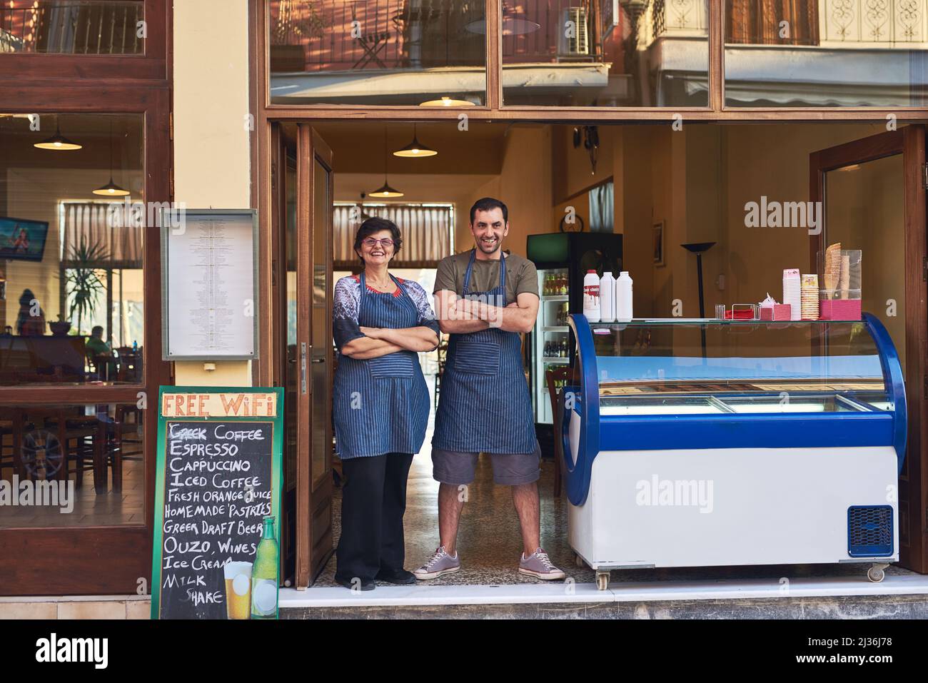 Dieser Laden ist seit Generationen in unserer Familie. Ganzkörperportrait einer reifen Frau und ihres erwachsenen Sohnes, der im Eingangsbereich zu ihrem steht Stockfoto