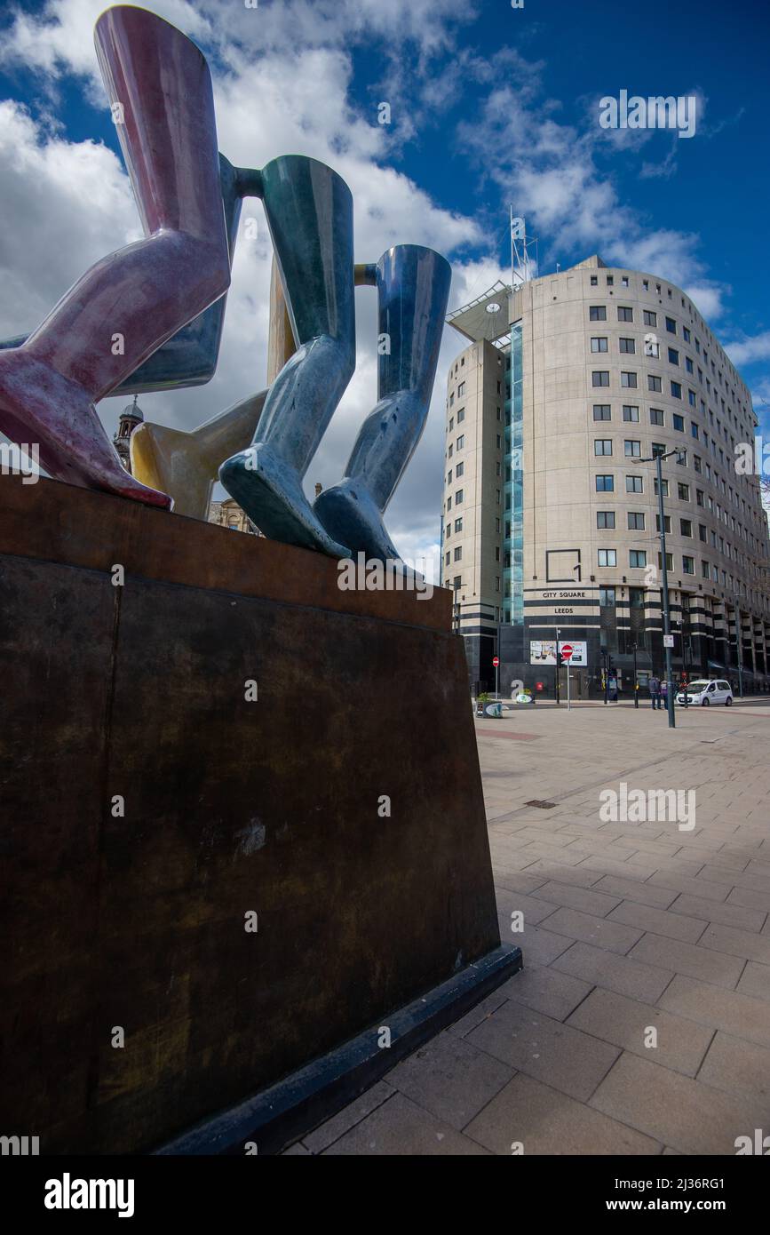 Beine gehen auf einer Skulptur von Kenneth Armitage, auf dem City Square, Leeds Stockfoto