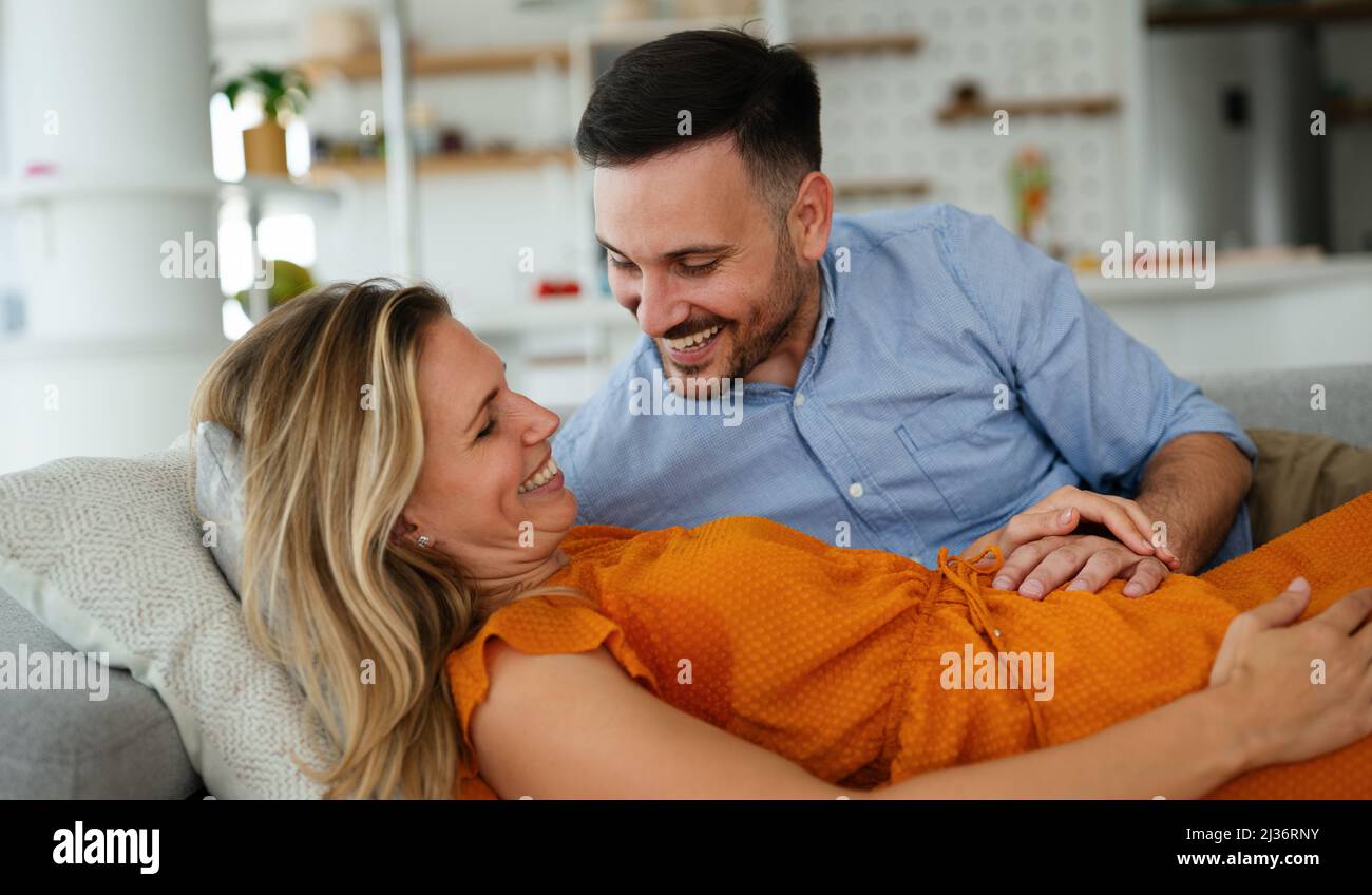 Glücklicher Mann berühren Bauch des lächelnden schwangere Frau auf sofa Stockfoto