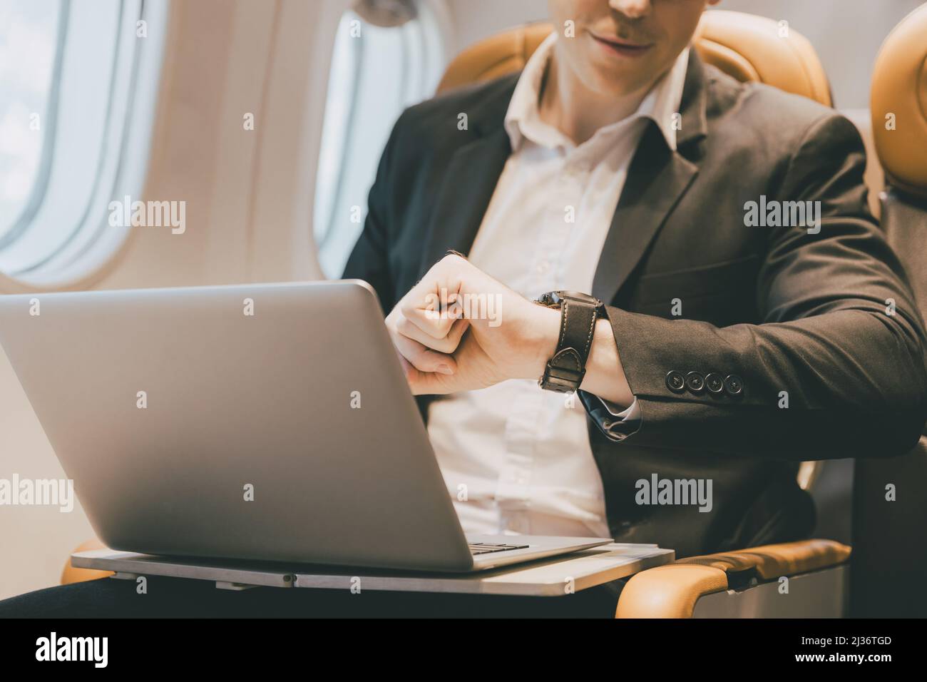 Business-Mann Blick auf Armbanduhr während der Flugreise. Lange Zeit zu spät und Sorgen über Flugplankonzept. Stockfoto