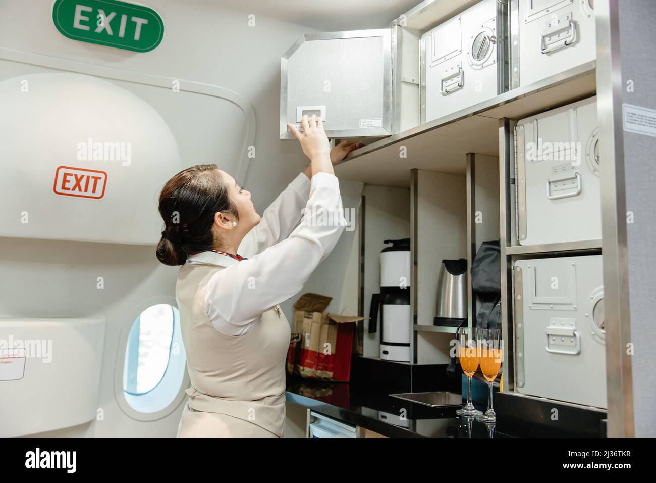 Die Flugbegleiterin bereitet Lebensmittel mithilfe des Sicherheitsschranks in der Flugkabine zu. Stockfoto