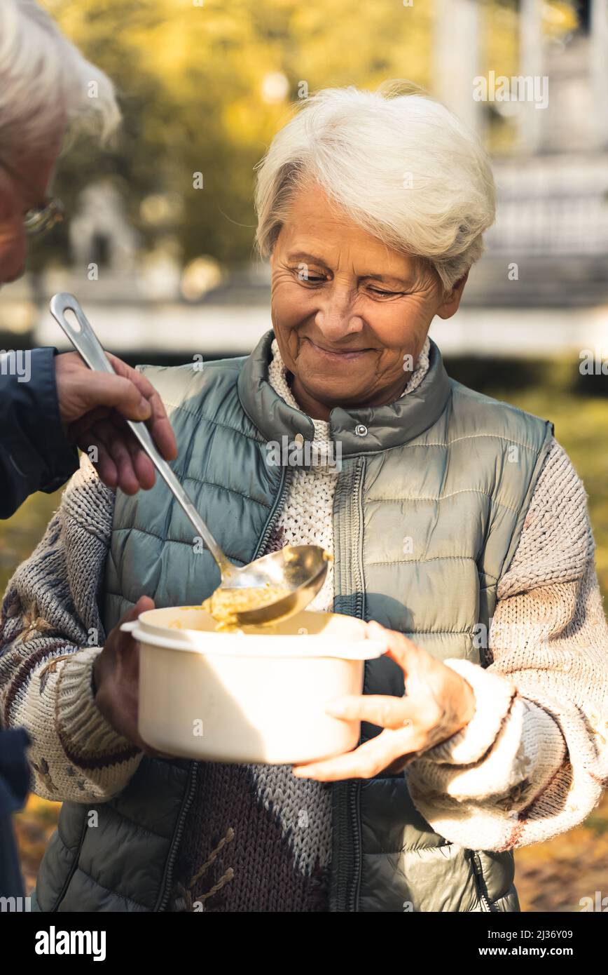 Ältere kaukasische Frau bekommt Nahrung von einem Mann Natur Hintergrund ältere Menschen Wohlbefinden Unterstützung Konzept Medium shot selektiver Fokus . Hochwertige Fotos Stockfoto