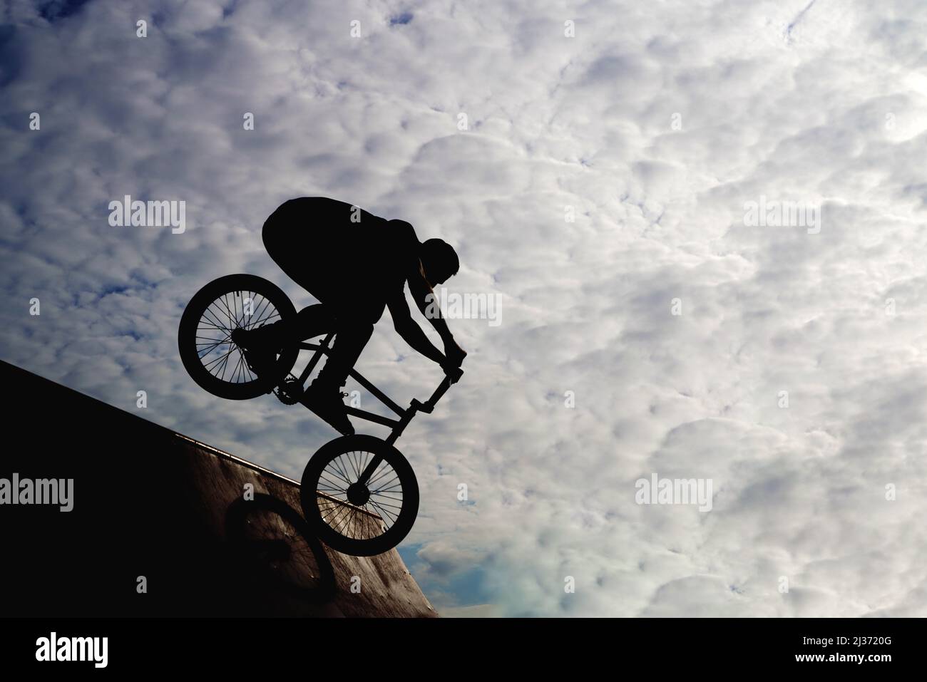 Silhouette eines jungen Mannes, der auf dem Fahrrad Extremsport betreibt. Hochwertige Fotos Stockfoto