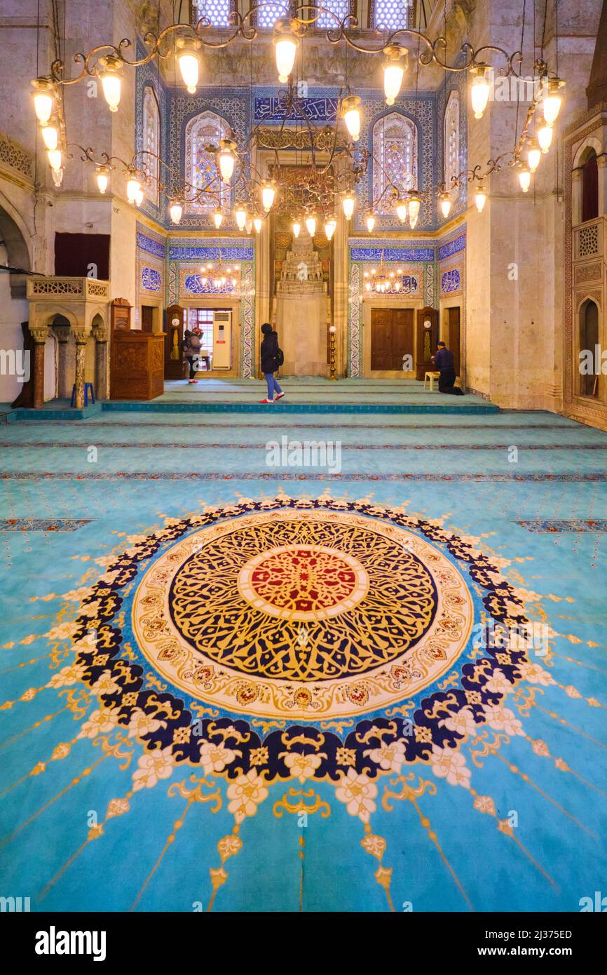 Ein Blick auf das große, runde, abstrakte Muster im blauen, grünen Teppich. In der Muradiye Moschee in Manisa, Türkei. Stockfoto