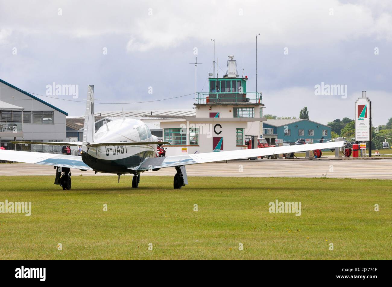 Mooney-Leichtflugzeug vor den Hangars und dem Kontrollturm am Sywell Aerodrome, Northamptonshire, Großbritannien, während eines Royal Aero Club-Flugrennens Stockfoto