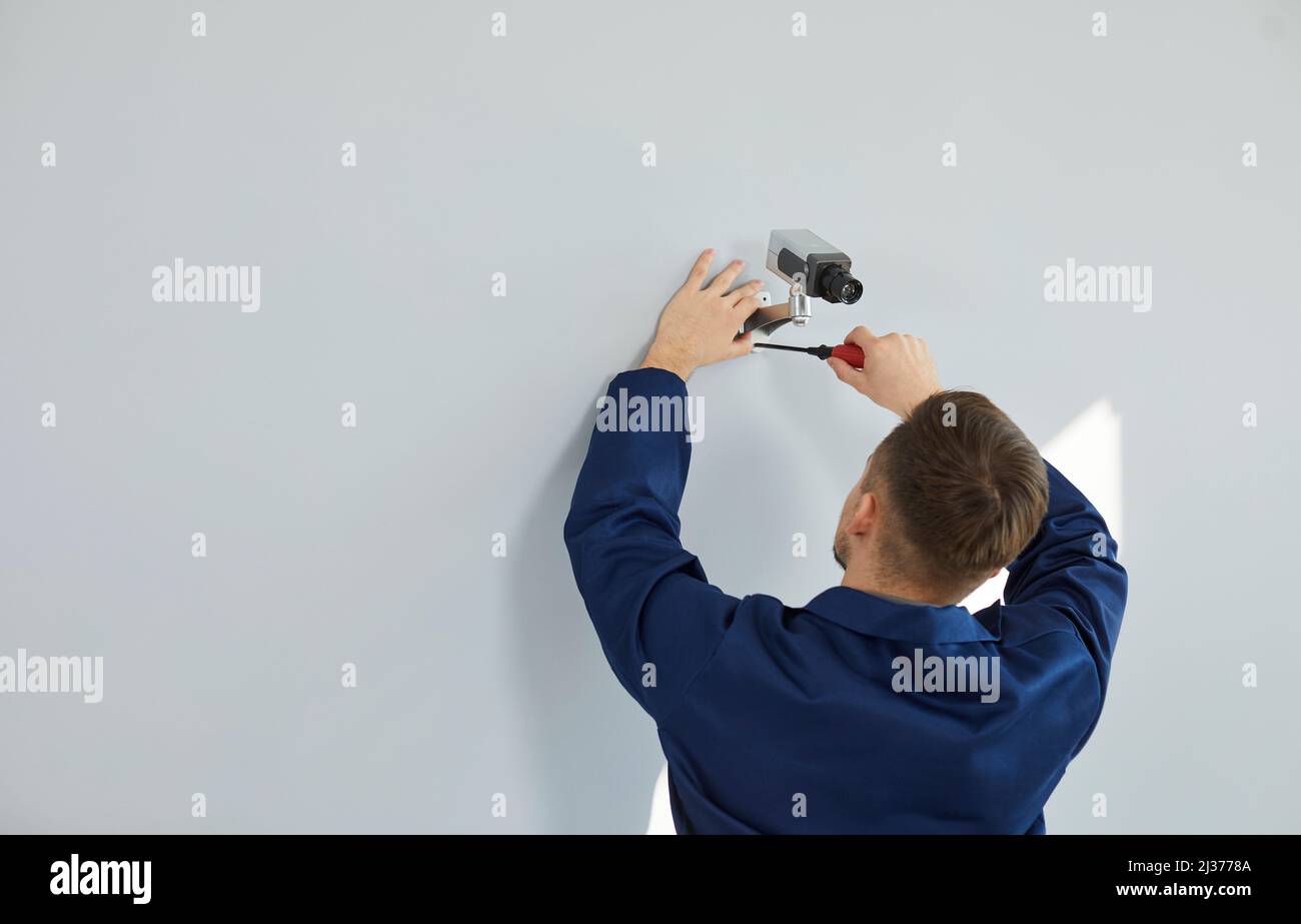 Ein professioneller männlicher Techniker montiert eine Videoüberwachungskamera an der Wand des Hauses oder Büros. Stockfoto