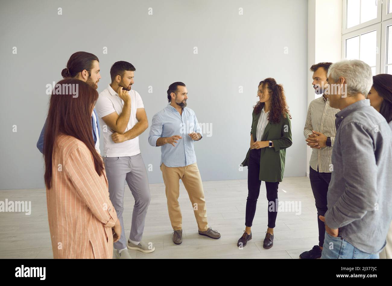 Eine Gruppe von Männern und Frauen, die im Büro stehen und mit einem Business Trainer diskutieren Stockfoto