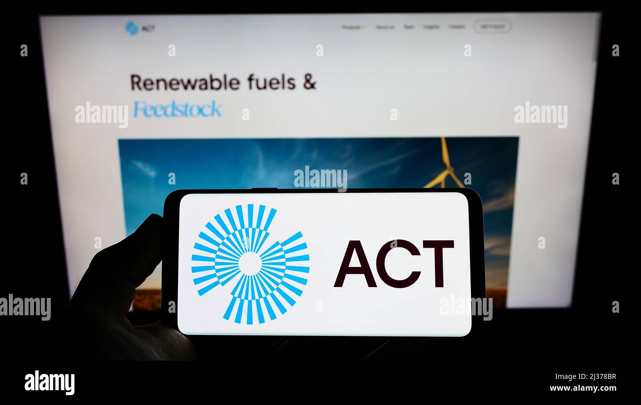 Person, die ein Mobiltelefon mit dem Logo des niederländischen Unternehmens ACT Commodities Group BV auf dem Bildschirm vor der Unternehmenswebseite hält. Konzentrieren Sie sich auf die Telefonanzeige. Stockfoto