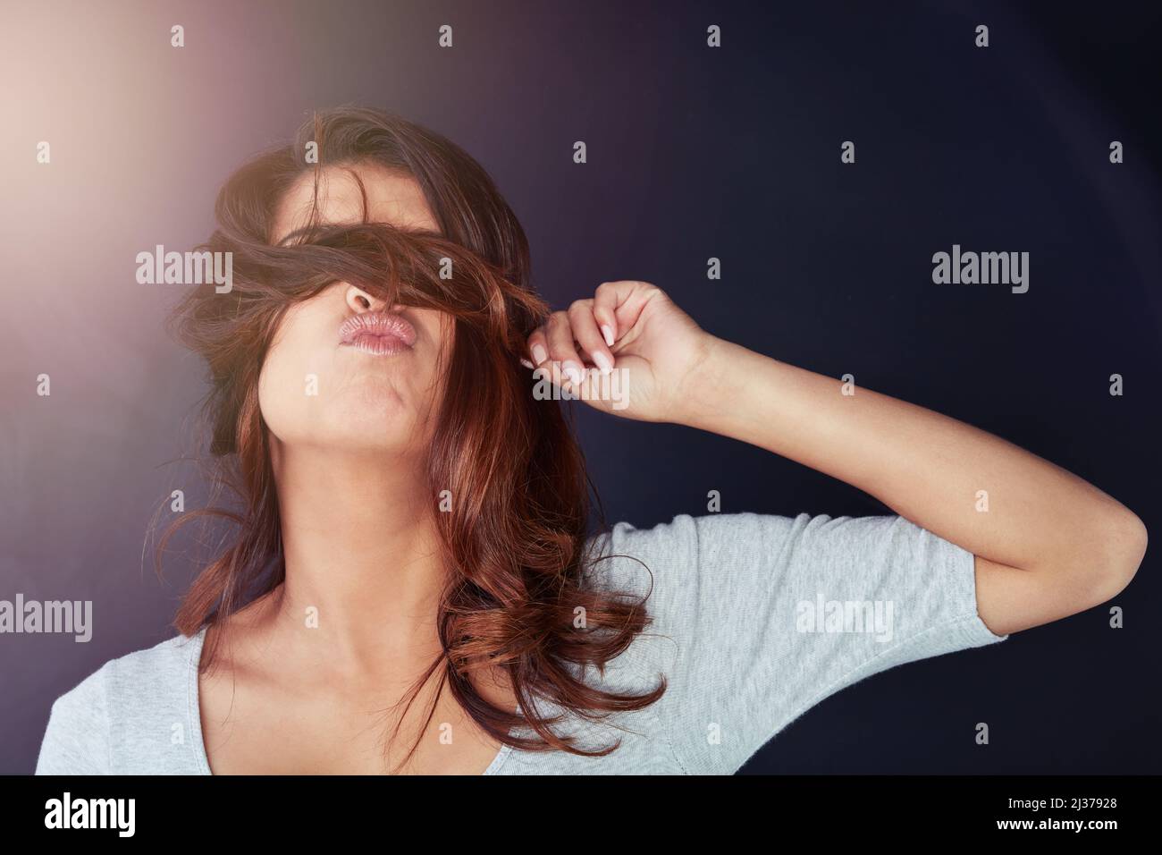 So ein Haar haben Sie noch nie gesehen. Ausgeschnittene Aufnahme einer schönen jungen Frau, die im Studio mit ihren Haaren über ihren Augen posiert. Stockfoto