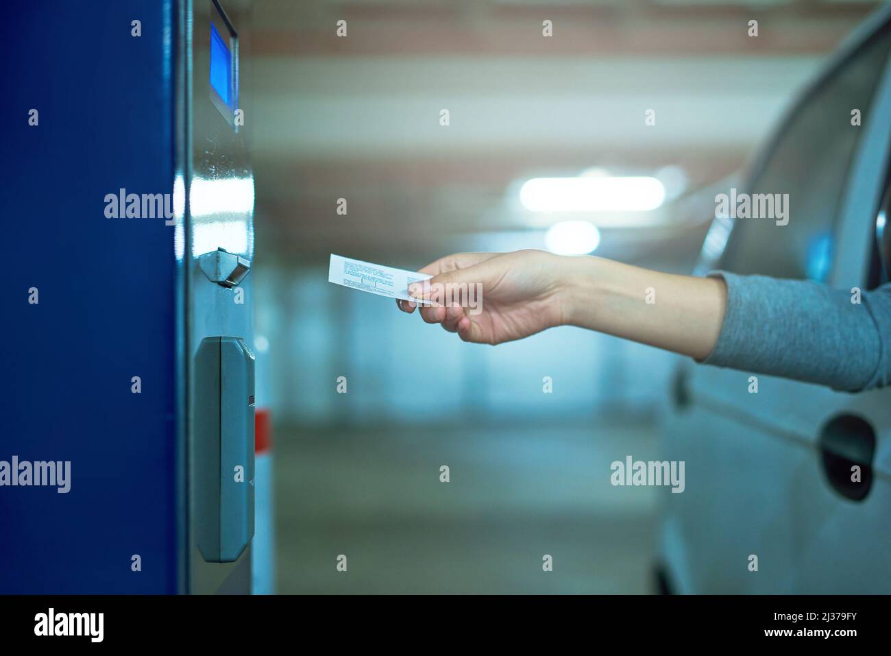 Nur außerhalb der Reichweite. Aufnahme eines nicht erkennbaren Fahrers, der ein Ticket in eine Parkuhr einführt. Stockfoto