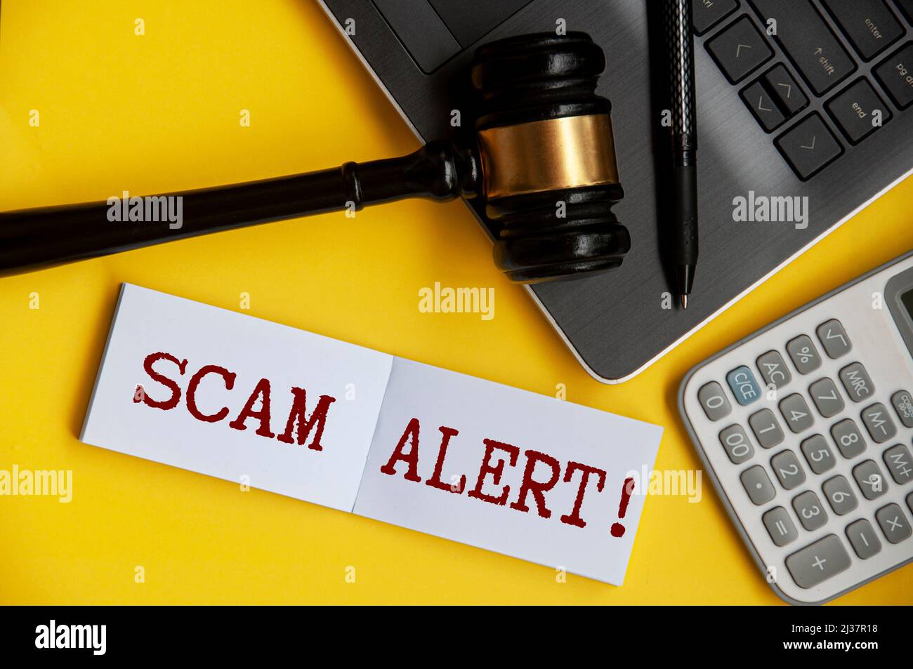 Scam-Warntext auf Notizblock mit Hintergrund für Gavel, Laptop, Stift und Rechner. Stockfoto