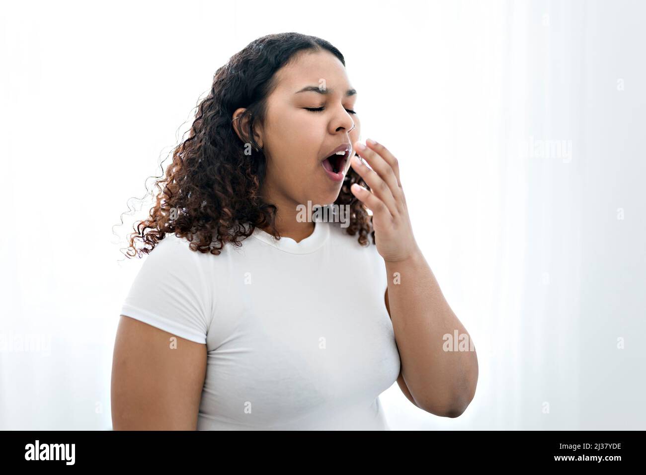 Junge afroamerikanische Frau gelangweilt gähnend müde, den Mund mit der Hand bedeckend Stockfoto