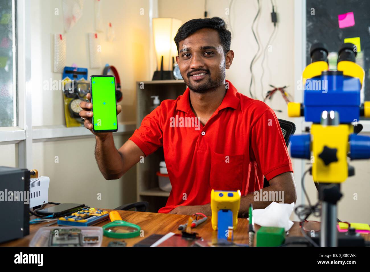 Glückliche Werkstatt zeigt Green-Screen-Handy durch Blick Kamera im Geschäft - Konzept der Online-Reparatur-Buchung Service, App-Promotion und Stockfoto