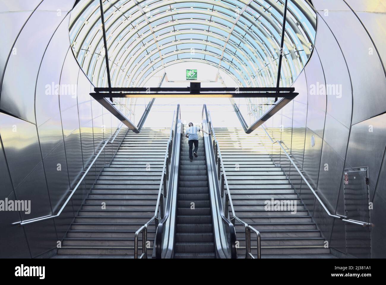 Treppe und Rolltreppe, gebogenes Glasdach über dem Eingang zur U-Bahn-Station „Hradčanská“ in Prag, Tschechien. Stockfoto