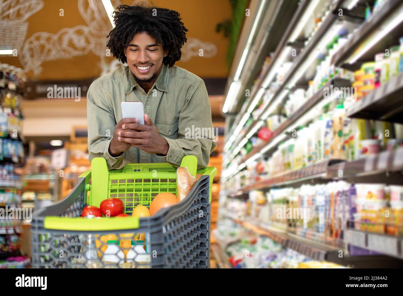 Fröhlicher Afrikanischer Mann Mit Handy Tun Lebensmittelgeschäft Einkaufen Im Laden Stockfoto