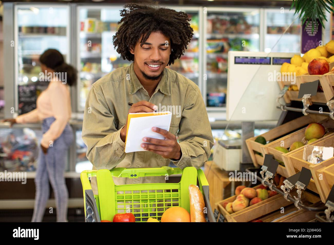 Happy African American Man Writing Lebensmittelgeschäft Einkaufsliste In Supermarkt Stockfoto