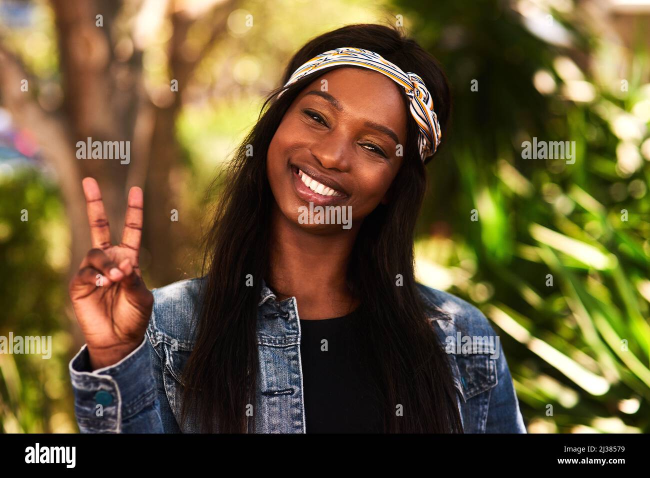 Frieden aus der Welt. Porträt einer attraktiven jungen Frau, die das Friedenszeichen macht, während sie sich im Park im Freien entspannt. Stockfoto