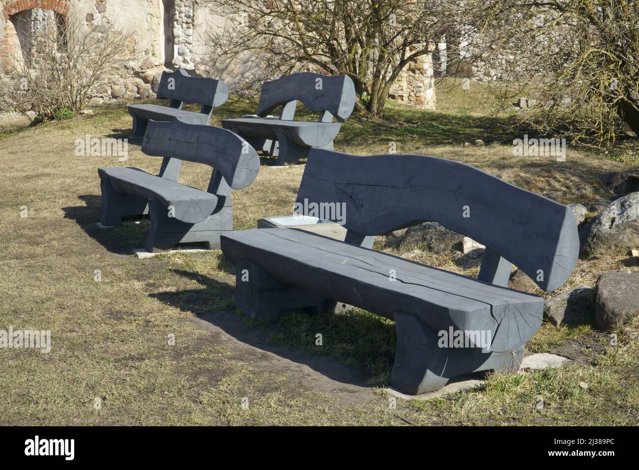 Landschaftsgestaltung mit rustikalen Holzbänken im historischen städtischen Umfeld. Tischlerei Tischlerarbeiten, die aus Rundholz Holz gemacht. Stockfoto