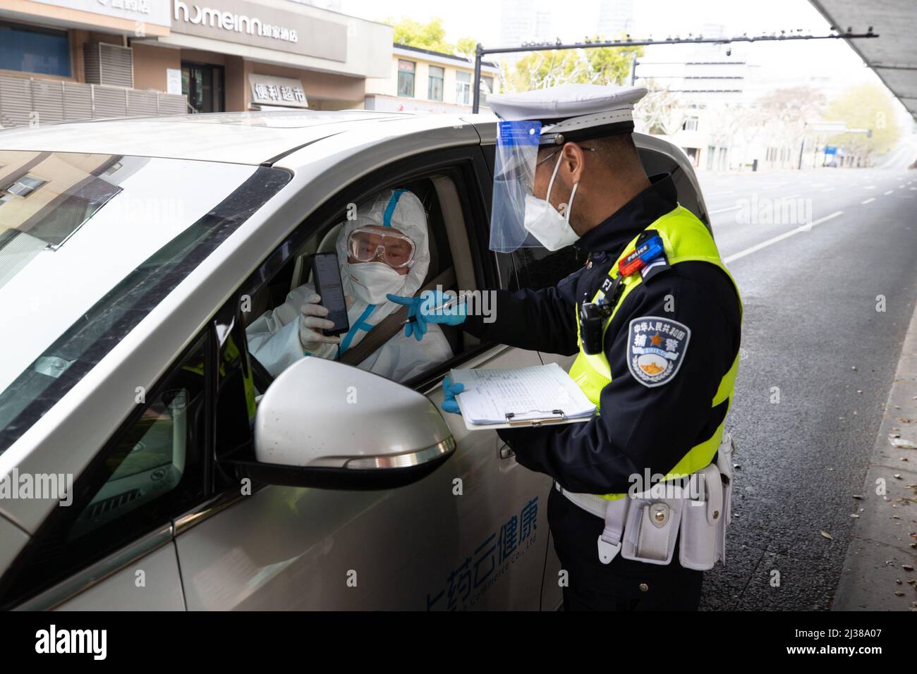 Shanghai, China. 5. April 2022. Ein Polizist überprüft den Sonderausweis und die persönlichen Informationen des medizinischen Befreiers Ye Yifei in Shanghai, Ostchina, 5. April 2022. Während der vorübergehenden geschlossenen Behandlungsdauer in Shanghai ist die Versorgung und Lieferung von Spezialmedikamenten an die Patienten, die diese benötigen, besonders wichtig. Eine Apotheke namens Shanghai Pharma E Pharmacy, die mehr als 260 neue Medikamente, Spezialmedikamente und Medikamente für seltene Krankheiten verkauft, bleibt im Geschäft, um die Medikamente zu liefern und zu liefern. Quelle: Jin Liwang/Xinhua/Alamy Live News Stockfoto