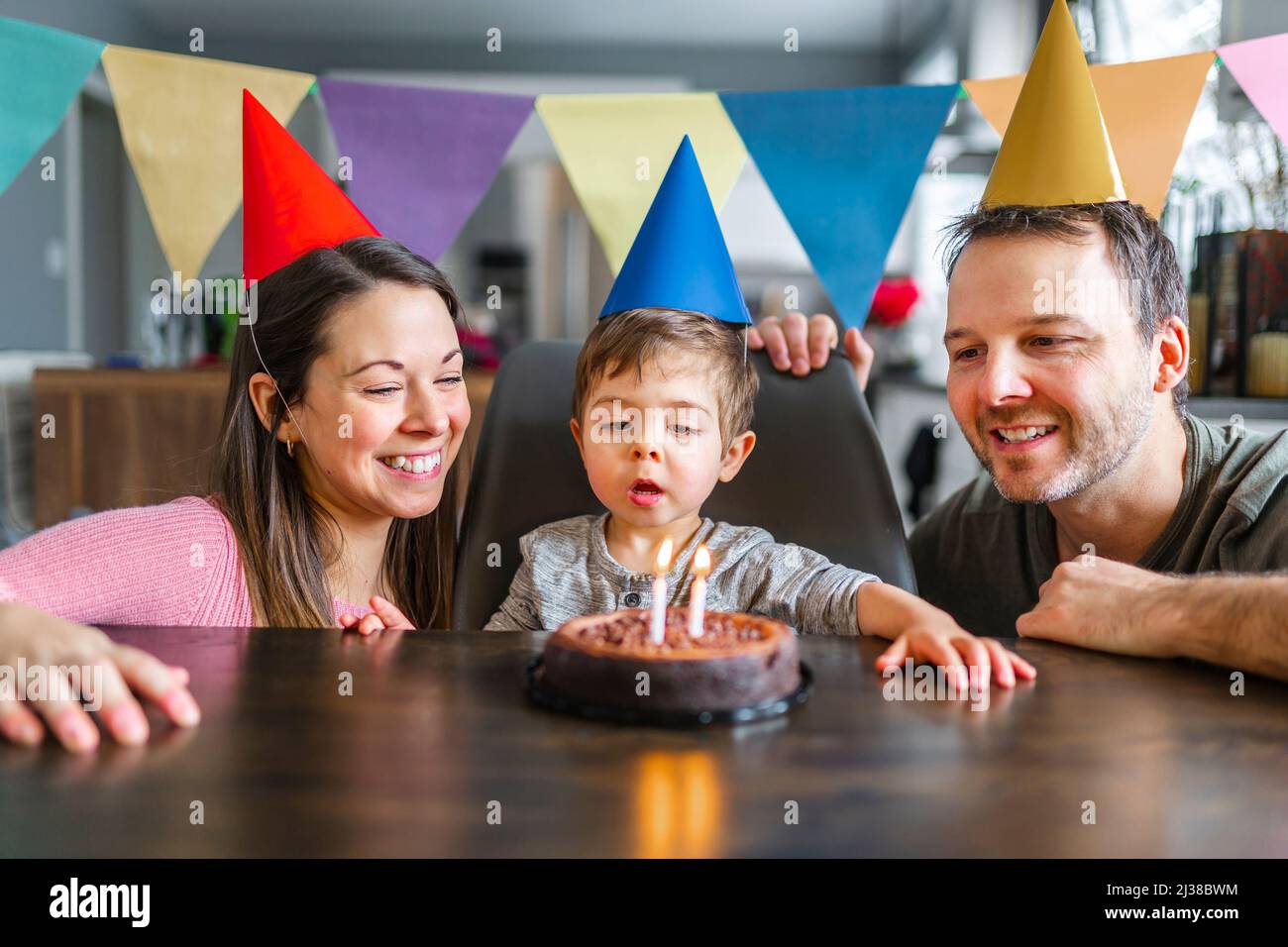 Porträt einer Familie, die zu Hause den zweijährigen Geburtstag des kleinen Jungen feiert Stockfoto