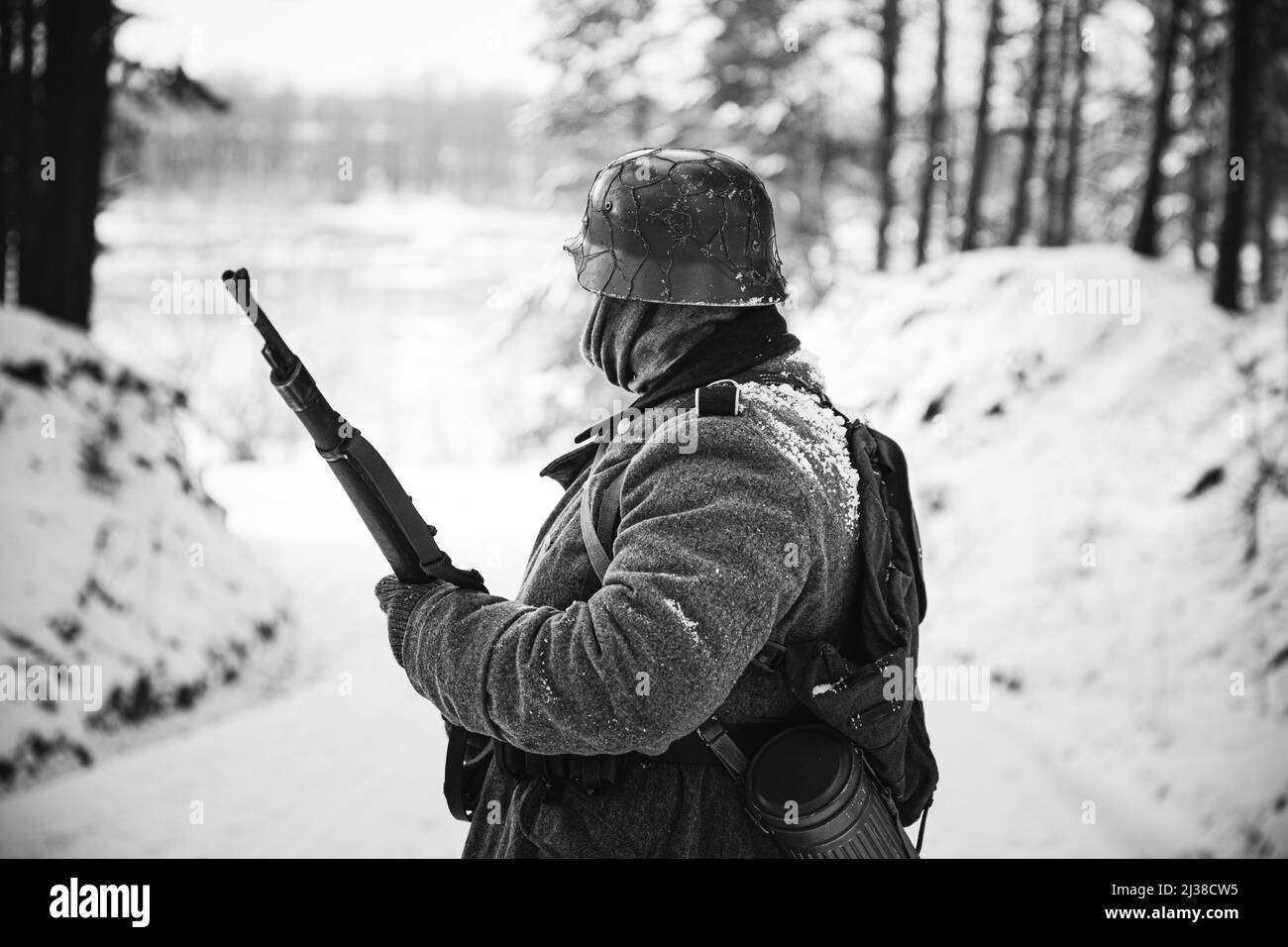 Re-enactor gekleidet wie deutscher Wehrmachts-Infanterie-Soldat im Zweiten Weltkrieg mit Gewehr im Winterwald. Schwarzweiß-Foto. 2. WELTKRIEG Stockfoto