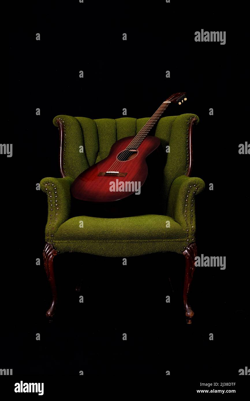 Schöne rote Gitarre auf einem grünen Vintage Armstuhl Stockfoto Schöne rote Gitarre auf einem grünen Vintage Armstuhl Stockfoto