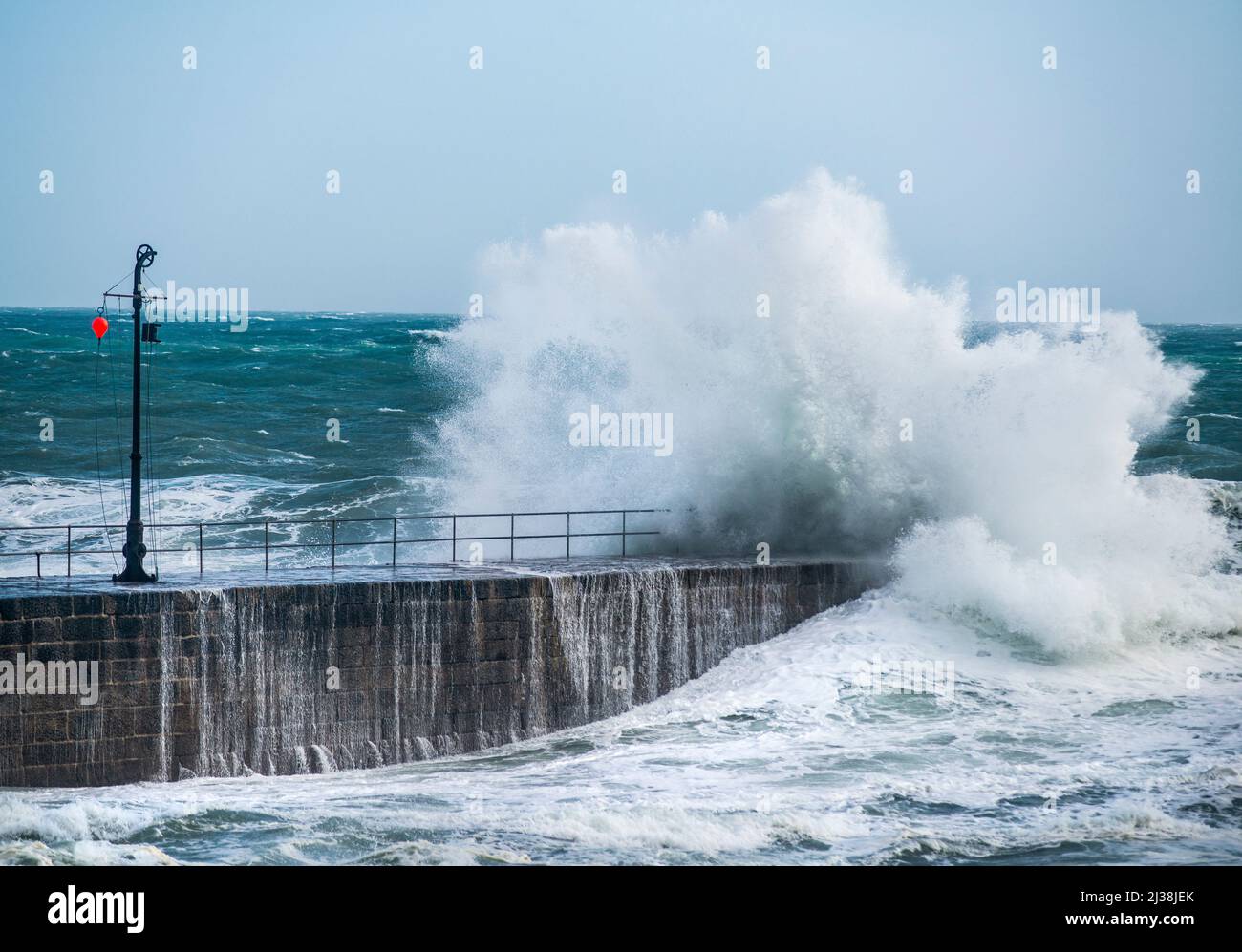 Wellen, die über die Hafenmauer bei Porthleven, Cornwall, England, UK Stockfoto