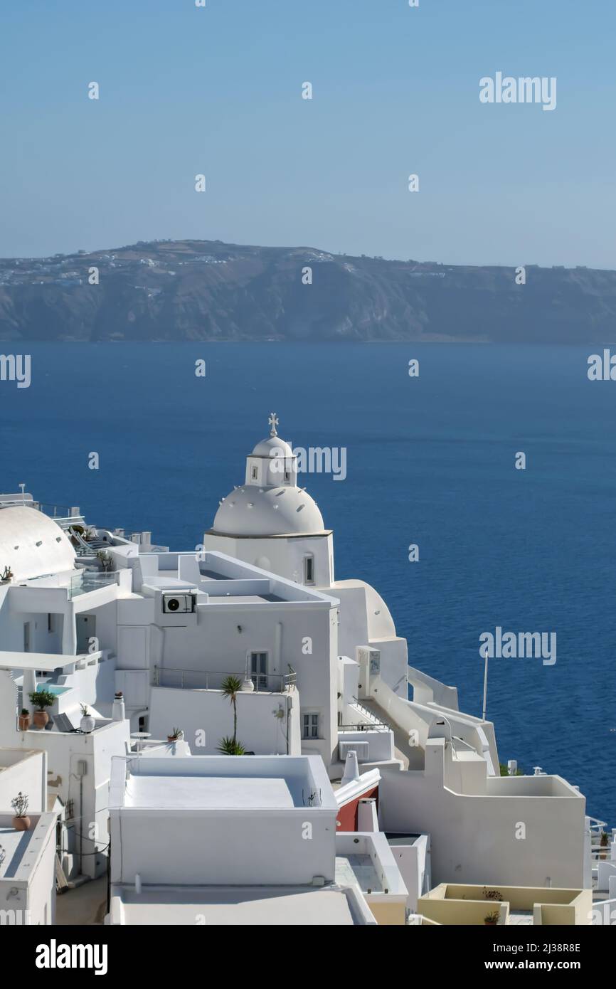 Blick auf eine weiß getünchte Kirche und Villen mit Blick auf die ägäis in Santorini Stockfoto