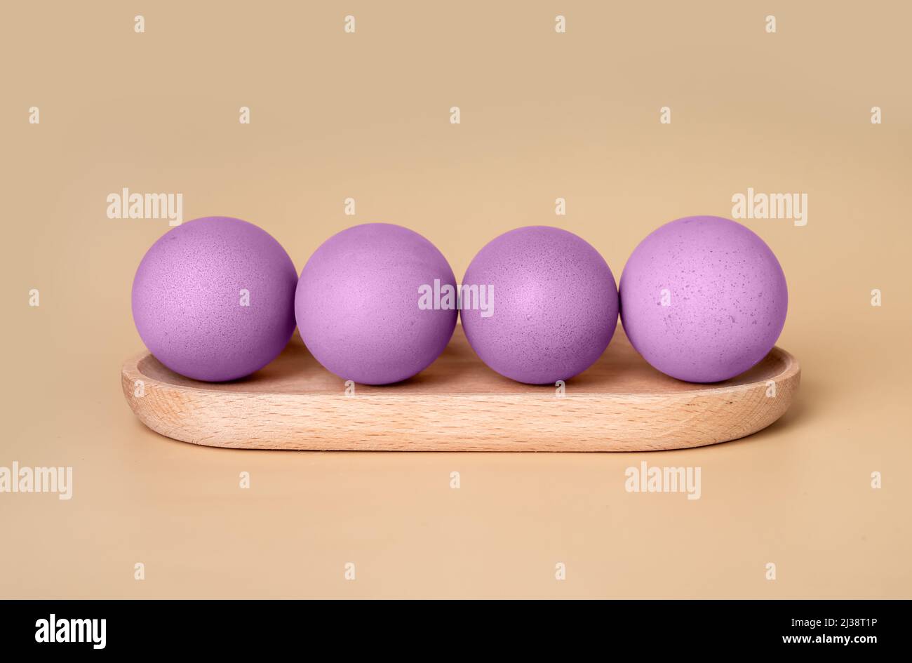Violett gefärbte Ostereier auf einem Holzserver auf beigem Hintergrund. Vorbereitung auf religiöse Feiertagsfeier Konzept im Minimalismus Stil. Hochwertige Fotos Stockfoto