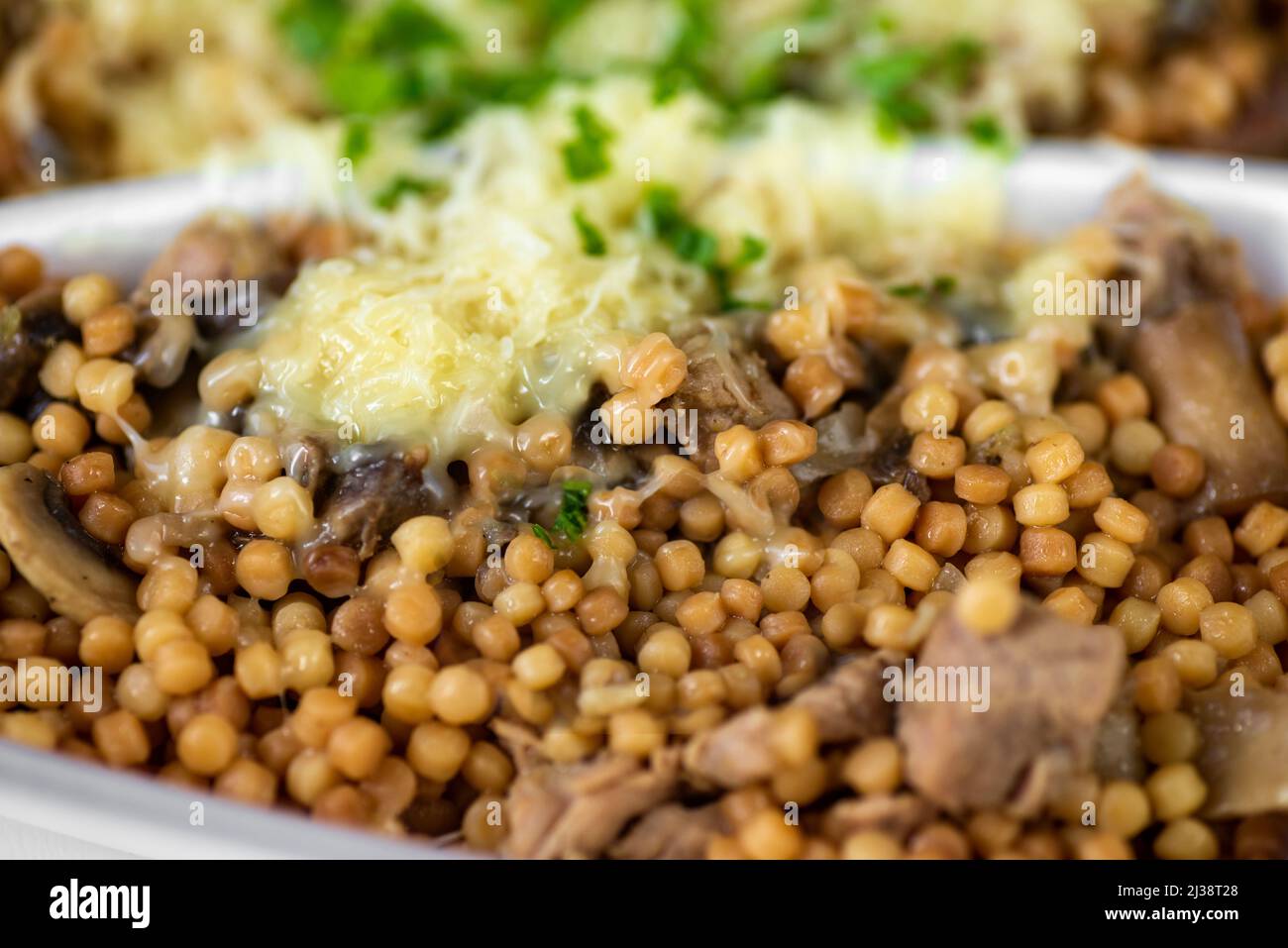 Runde Grieß-Pasta mit Schweinefleisch in Scheiben, Sauce, Pilz und geriebenem Käse und Schnittlauch in Kunststoffbox. Essen zum Mitnehmen, Nahaufnahme. Stockfoto