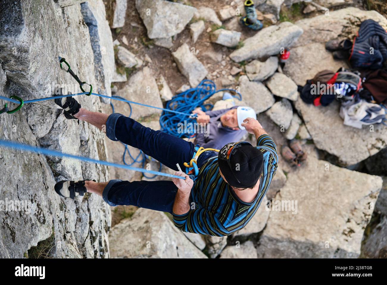 Ein Kletterer, der mit dem Seil nach dem Klettern an einer Felswand absteigt. Stockfoto