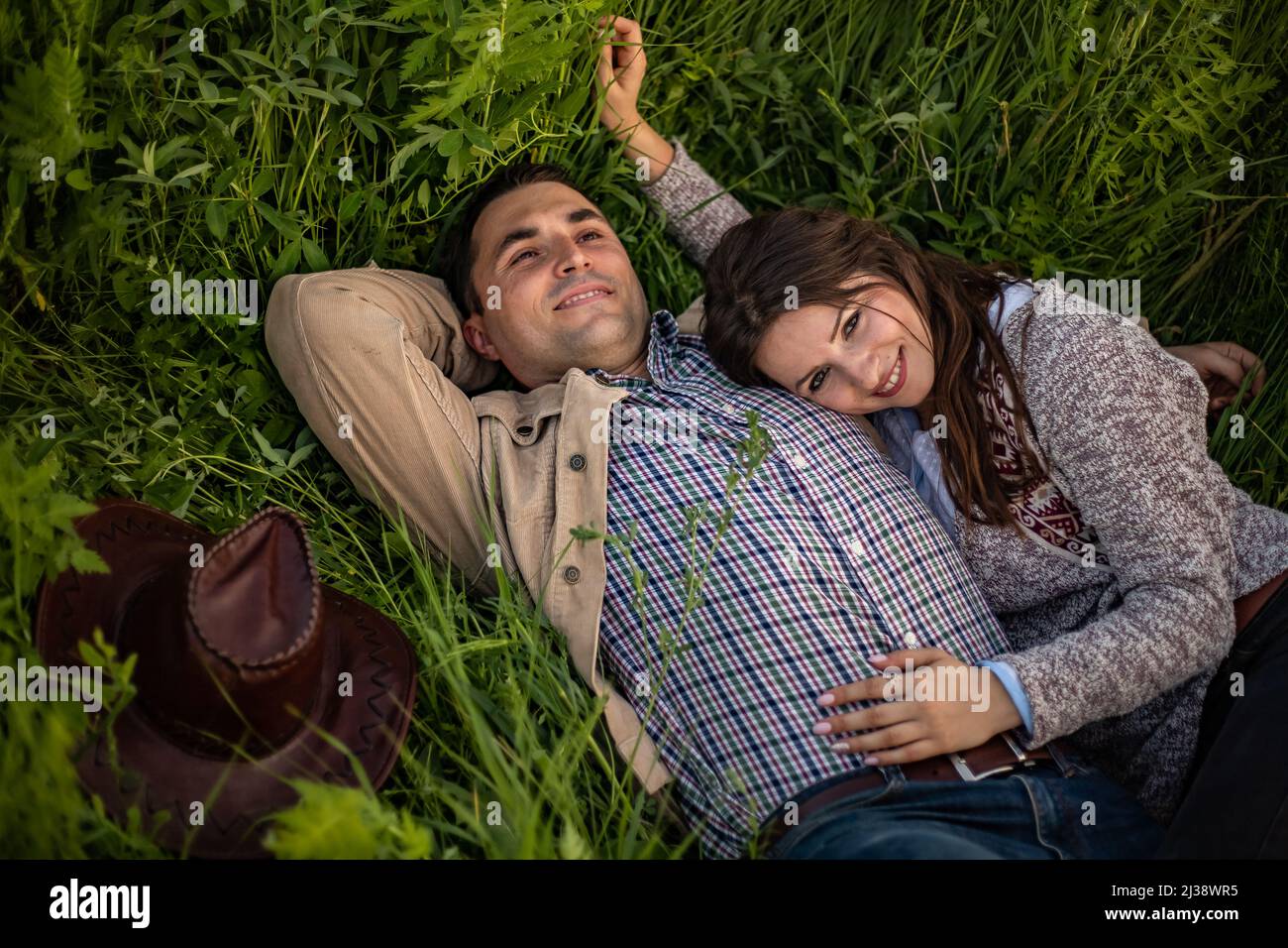 Junges Paar mit Picknick auf der Wiese an hellen sonnigen Tag. Mann und Frau genießen die Gesellschaft des anderen Stockfoto