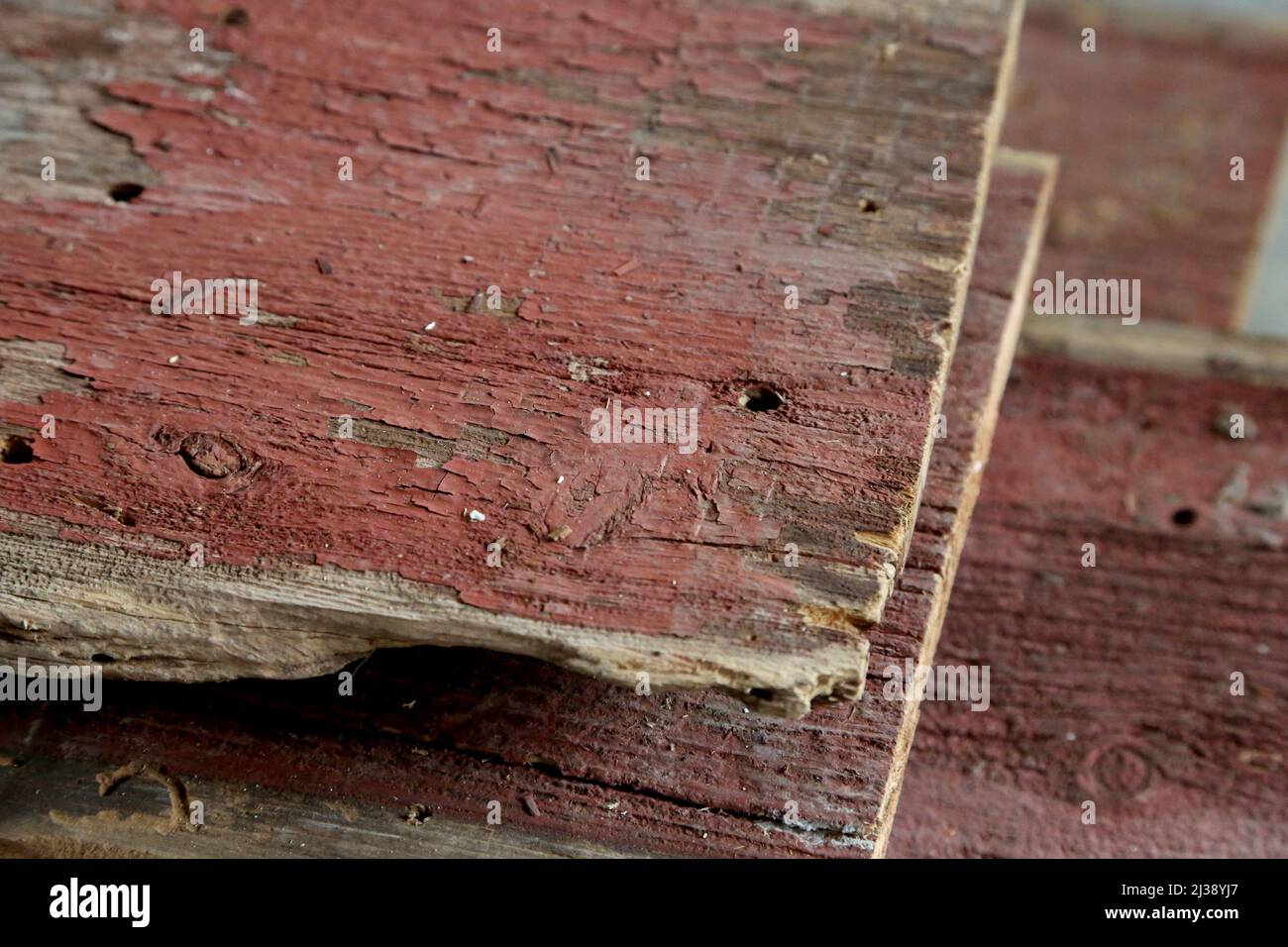Nahaufnahme eines Stapels verwitterter, roter Bretter, die aus einer alten Scheune geborgen wurden. Stockfoto