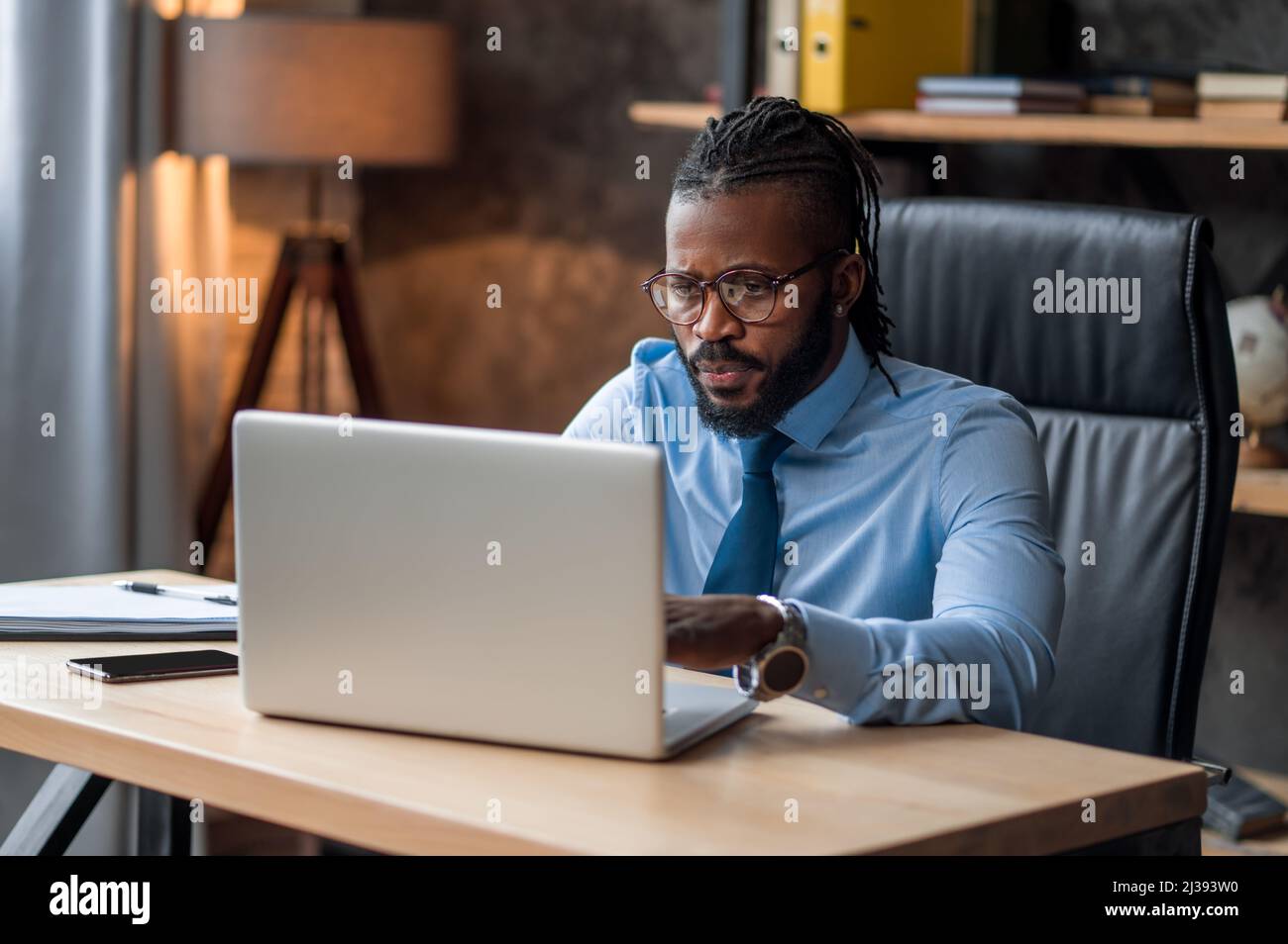 Konzentrierter Geschäftsmann in Brillen mit seinem Laptop Stockfoto