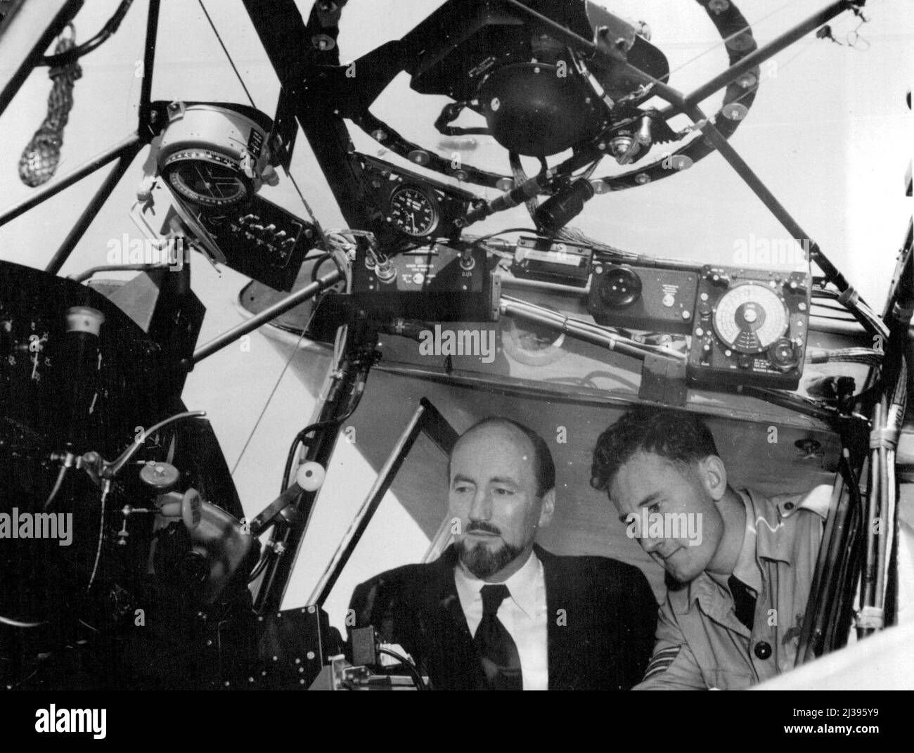 Herr P.G., Direktor der Antarktischen Abteilung des Außenministeriums Gesetz, ist das Cockpit des Auster von Sgt gezeigt. Pilot S.R.K. Seaver, zweiter Pilot der RAAF-Partei für Expedition. 30. November 1953. Stockfoto