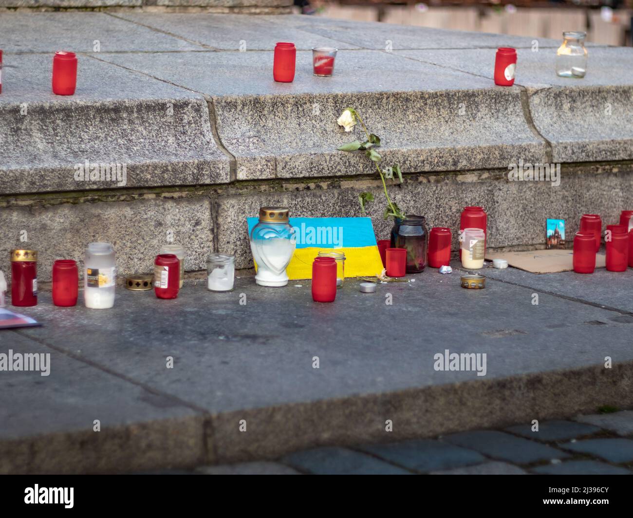 Kerzen und eine ukrainische Flagge, um den Krieg zwischen der Ukraine und Russland zu betrauern. Bürgersteig in der Stadt mit Symbolen einer Demonstration gegen das Militär. Stockfoto