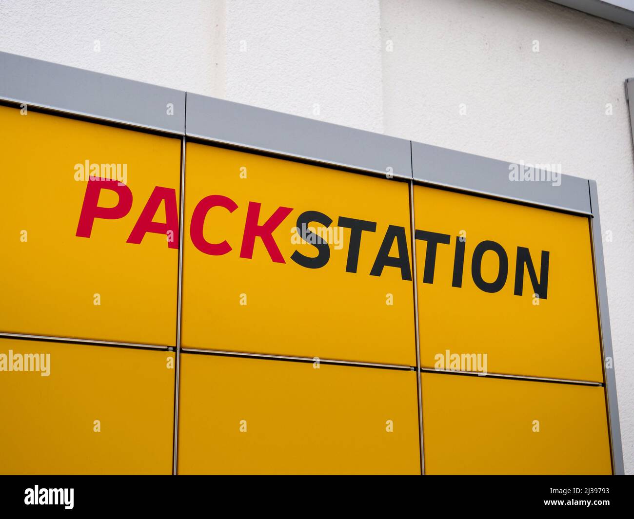 DHL Packstation Logo auf einem gelben Schließfach neben einem Gebäude. Briefe der Verpackungsstation, um Pakete von überall zu empfangen. Stockfoto
