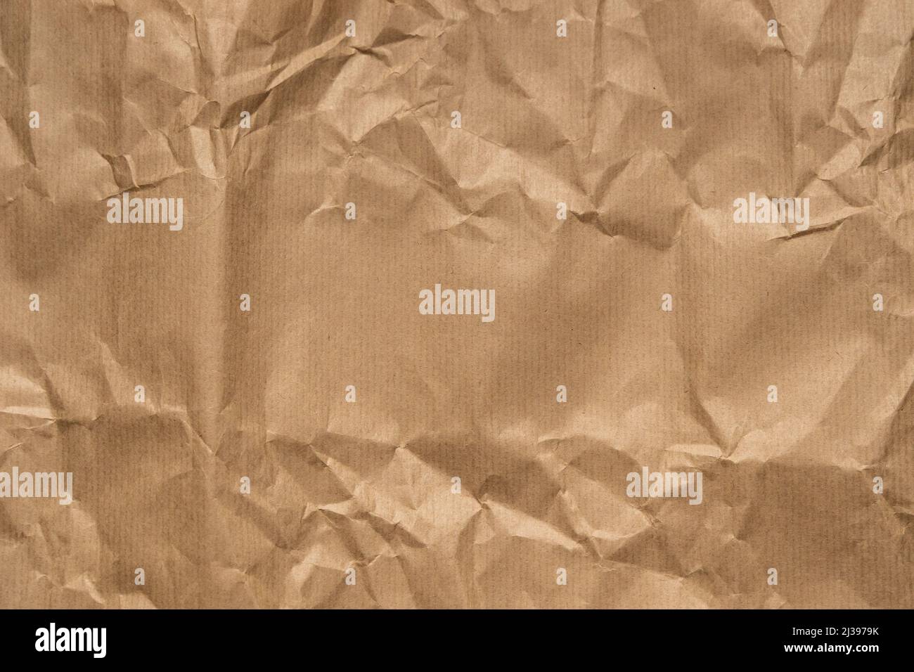 Braunes Verpackungspapier mit Falten Hintergrundtextur. Zerkratztes Blatt aus Pappe. Hintergrund aus Karton für ein Design. Strukturpapier. Stockfoto
