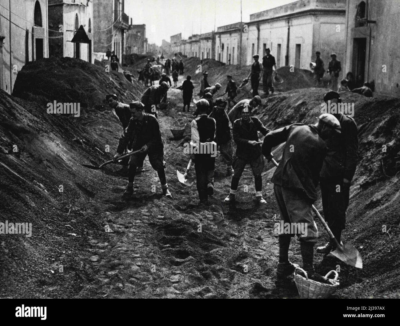 Italiener Clear Mt. Trümmer des Vesuvs - italienische Soldaten und Zivilisten in einer Stadt in der Nähe des Mt. Der Vesuv entfernt die Straßen der Lapilli (Lava in Form von kleinen Steinen), die während des schlimmsten Ausbruchs des italienischen Vulkans seit mehr als 70 Jahren auf das Land fielen. Alliierte Beamte halfen dabei, Zivilisten aus dem Gebiet zu evakuieren und Notstationen für die Hilfe für Obdachlose und Verletzte einzurichten. 10.Mai 1944. (Foto vom US Office of war Information Picture). Stockfoto